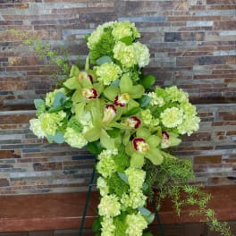 Green floral cross with orchids and pale blooms on an easel