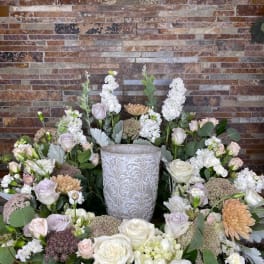 Symmetrical floral arrangement around a decorative urn with white and blush blooms