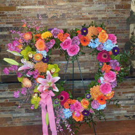 Large floral wreath on an easel with pink, orange, yellow, and blue blooms