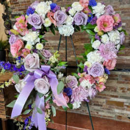 Heart-shaped floral wreath with lavender roses and pink blooms on an easel