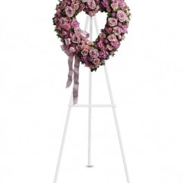 Heart-shaped pink rose wreath on a white easel with ribbon