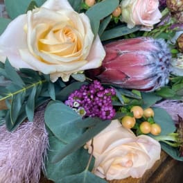 Bouquet with cream roses, a pink protea, and purple filler flowers