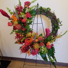 Large floral wreath on a metal stand with red, orange, and pink blooms