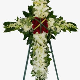 Standing floral cross with white lilies and red roses on an easel