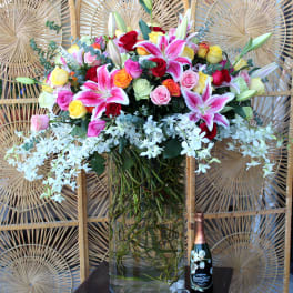 Mixed bouquet of roses and lilies in a tall glass vase