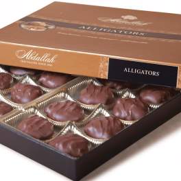 Open box of milk chocolate candies in a gold tray with a brown branded lid partially covering them