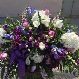 Large floral spray with white, pink, and purple flowers and a purple ribbon
