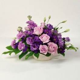 Pink and purple rose arrangement in a low white vase