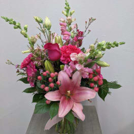 Pink lily and mixed flower bouquet in a clear glass vase