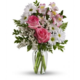 Mixed bouquet of pink roses, white daisies, and pink alstroemeria in a clear glass vase