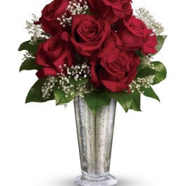 Tall silver vase filled with red roses and small white filler flowers