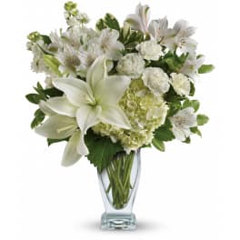 White lilies, carnations, hydrangea, and alstroemeria arranged in a clear glass vase