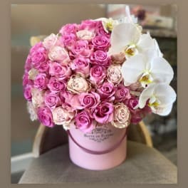 Pink roses and white orchids arranged in a pink hat box
