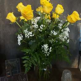 Yellow roses in a clear glass vase with white filler flowers