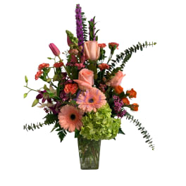 Mixed bouquet in a clear glass vase with pink roses, gerbera daisies, and green hydrangea