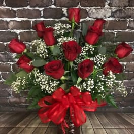 Red roses in a vase with baby's breath and a red ribbon bow