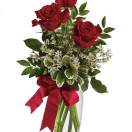Red roses in a clear glass vase with a red ribbon