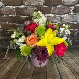 Mixed bouquet in a pink vase with a yellow lily and colorful blooms
