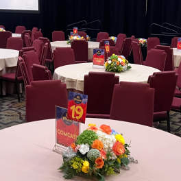 Round tables with small floral centerpieces and numbered signs in a banquet room