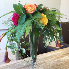 Mixed roses and calla lilies in a tall glass vase