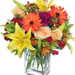Colorful bouquet of lilies, roses, and daisies in a clear glass vase
