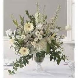 White floral arrangement in a clear vase with tall stems and trailing greenery