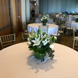 White floral centerpiece in a green vase on a round table