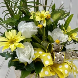 Basket arrangement with white roses, yellow daisies, and a large yellow ribbon