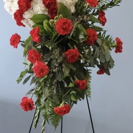 Standing floral spray with white and red carnations on a black easel