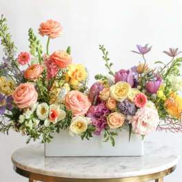 Mixed pastel flower arrangement in a white rectangular vase
