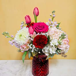 Mixed bouquet of pink and white flowers in a red glass vase