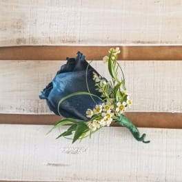 Dark blue rose boutonniere with small white flowers and greenery