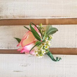 Pink rose boutonniere with small white flowers and greenery