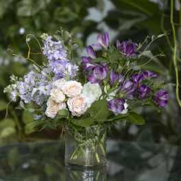 Purple and blush flowers arranged in a clear glass vase