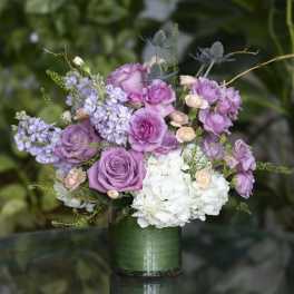 Lavender roses and white hydrangeas in a green glass vase
