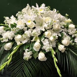 White floral casket spray with lilies, roses, and orchids