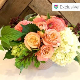 Peach roses and pale hydrangeas in a patterned vase