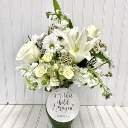 White floral arrangement in a glass vase with a memorial plaque