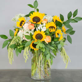 Sunflower and peach rose arrangement in a clear glass vase