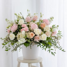 Pink and white roses arranged in a white pot