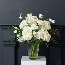 White roses and hydrangeas arranged in a clear glass vase