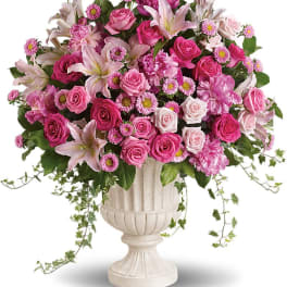 Pink mixed flower arrangement in a white urn vase