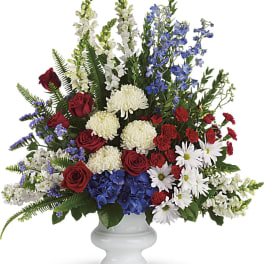 Red roses, white flowers, and blue blooms in a white vase