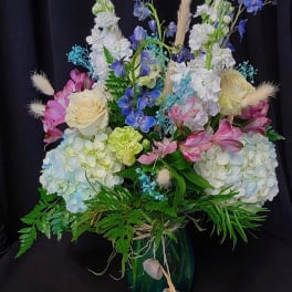 Mixed bouquet of pastel flowers in a dark vase
