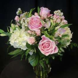 Pink roses and white hydrangeas arranged in a clear glass vase