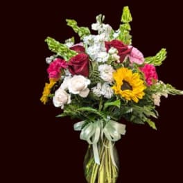 Mixed bouquet in a glass vase with roses, sunflowers, and white blooms