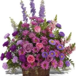 Basket arrangement of pink roses, purple daisies, and tall lavender blooms.