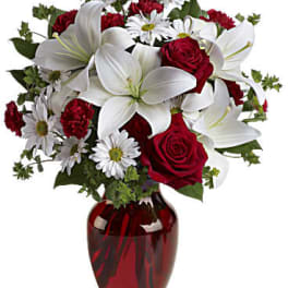 Red roses and white lilies in a red glass vase