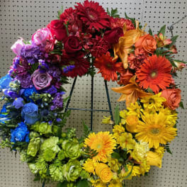 Rainbow heart-shaped floral wreath on a metal stand