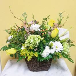 Mixed floral arrangement in a woven basket with yellow tulips and white daisies